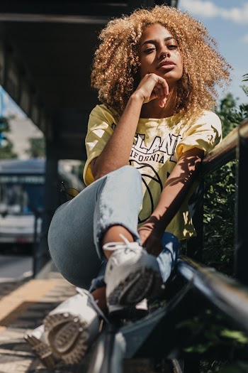 Photo of Woman in Yellow T-shirt and Blue Denim Jeans Sitting on Bench
