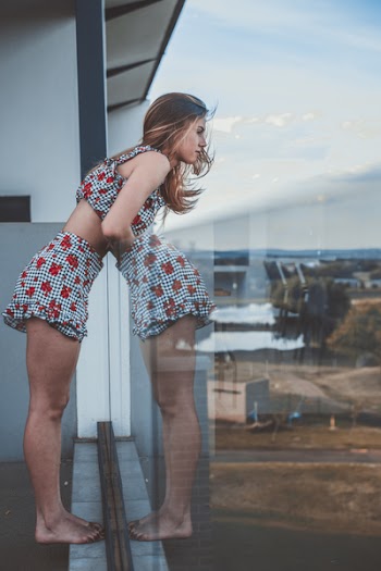 Photo of Woman Leaning Against Glass Balcony