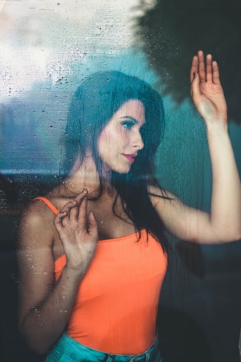 Photo of Woman Leaning Against Window Looking Outside