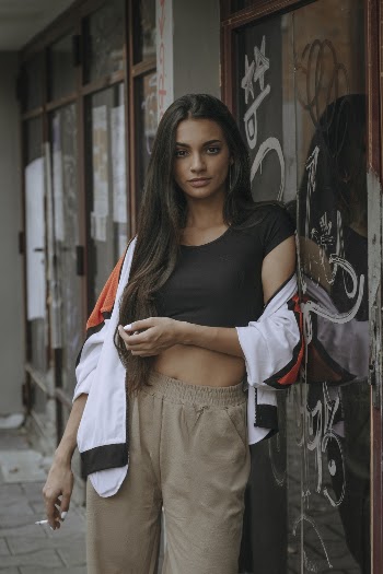 Photo of Woman Leaning on Glass Door Holding Cigarette
