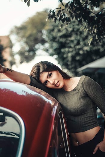 Photo of Woman Leaning on Red Vehicle