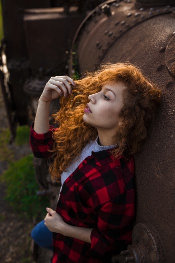 Photo of Woman Leaning on Rusty Metal Tank