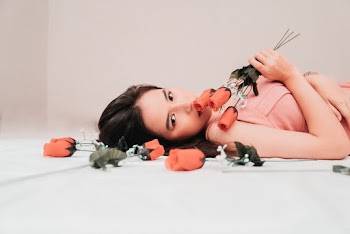 Photo of Woman Lying Down While Holding Red Roses