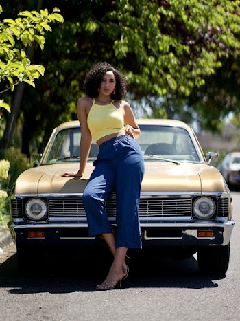 Photo of Woman Posing While Leaning on Hood of Parked Car