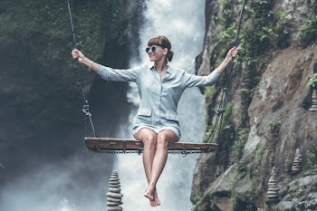 Photo of Woman Riding Swing in Front of Waterfalls