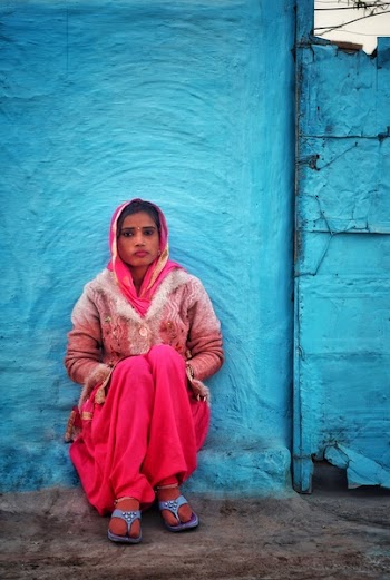 Photo of Woman Sitting Against a Concrete Wall