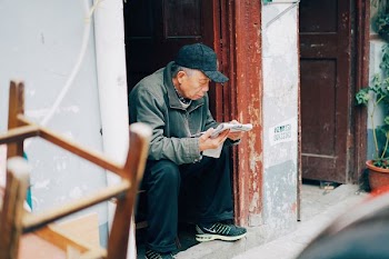 photo of woman sitting and reading newspaper