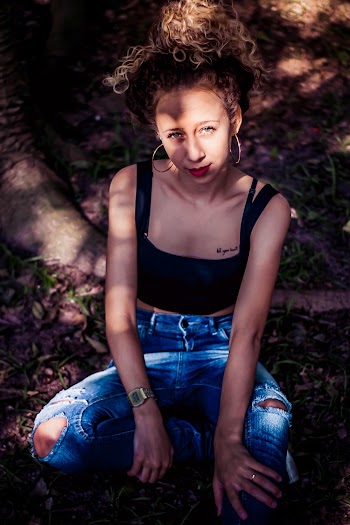 Photo of Woman Sitting and Wearing Ripped Jeans