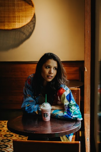 Photo of Woman Sitting at Table With a Starbucks Drink