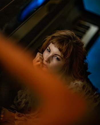 Photo of Woman Sitting Beside a Grand Piano