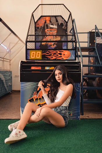 Photo of Woman Sitting Beside Basketball Arcade Machine Posing