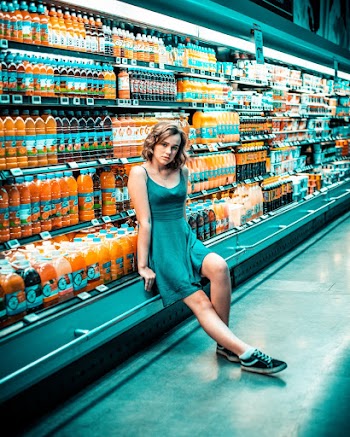Photo of Woman Sitting Beside Beverage Section in Grocery Store