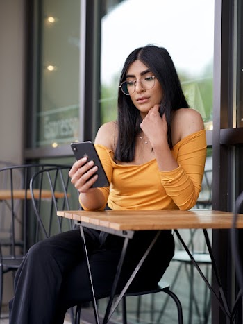 Photo of Woman Sitting by Table Using Smartphone