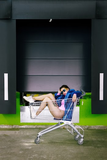 Photo of Woman Sitting Inside Shopping Cart Posing