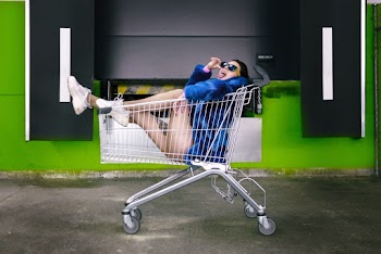 Photo of Woman Sitting Inside Shopping Cart Posing With Her Tongue Out