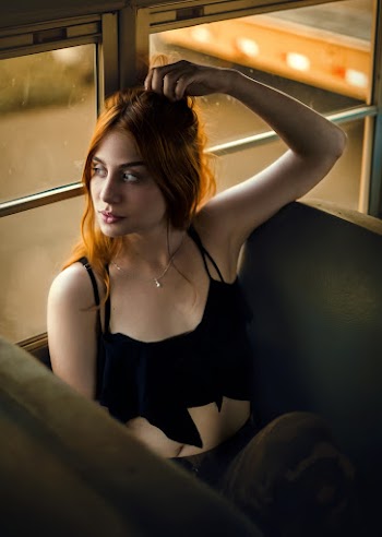 Photo of Woman Sitting Inside Vehicle Touching Her Hair While Looking Outside