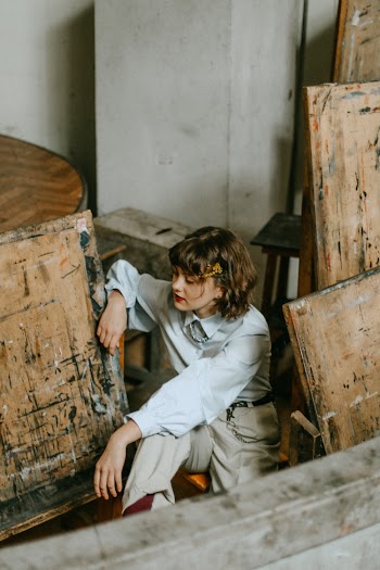 Photo of Woman Sitting Next to Painting Easels Posing