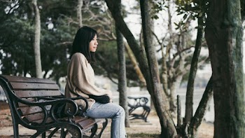 Photo of Woman Sitting on Bench Near Trees