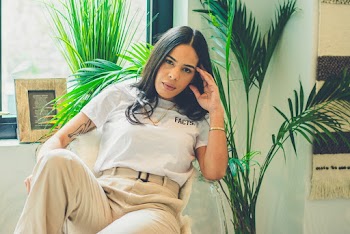 Photo of Woman Sitting on Chair Posing With Her Left Hand on Her Head