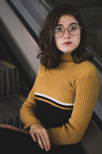 Photo of Woman Sitting on Escalator Stair Wearing Eyeglasses