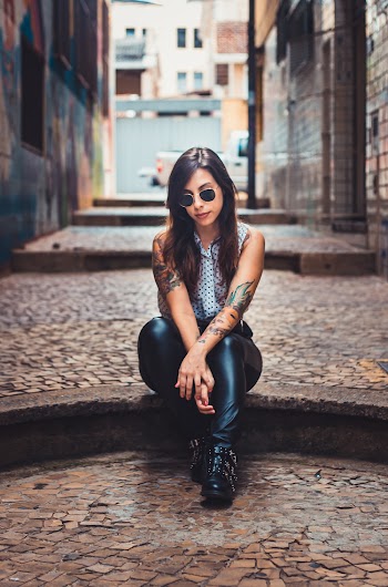 Photo of Woman Sitting on Floor of Cobblestone Alleyway Between Buildings