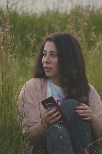 Photo of Woman Sitting on Grass While Holding Smartphone