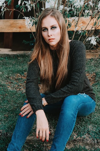 Photo of Woman Sitting on Grasses Near White Flowers Posing
