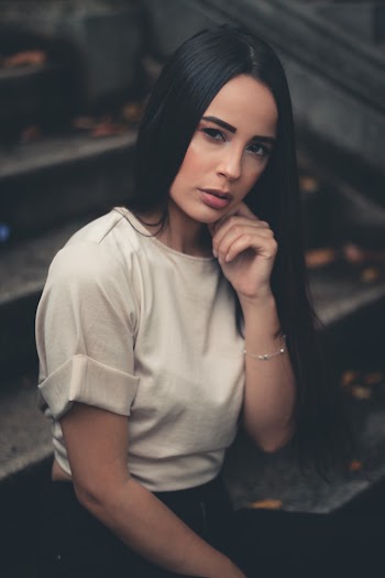 Photo of Woman Sitting on Gray Stairs Posing with Hand on Cheek