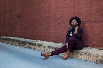 photo of woman sitting on ground in front of brown wall