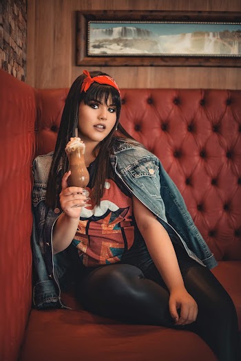 Photo of Woman Sitting on Red Couch While Posing with a Glass of Frappe Coffee 