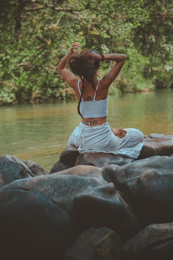 Photo of Woman Sitting on Rock Beside River