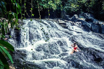 Photo of Woman Sitting on Rocks Near Waterfalls