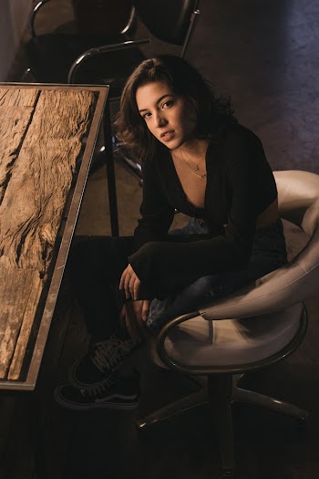 Photo of Woman Sitting on Rolling Chair Near Wooden Table Posing