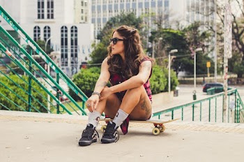 Photo of Woman Sitting on Skateboard While Looking Away
