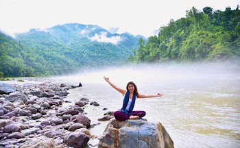 Photo of Woman Sitting on Stone Next to Body of Water