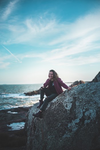 Photo Of Woman Sitting On Top Of The Rock