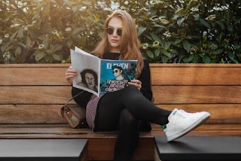 Photo of Woman Sitting on Wooden Bench While Reading Magazine