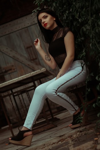 Photo of Woman Sitting on Wooden Chair Near Leaves