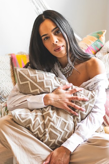 Photo of Woman Sitting on Wooden Floor While Hugging a Pillow