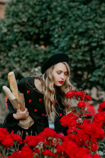 Photo of Woman Smelling Red Flowers