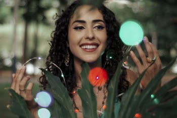 Photo of Woman Smiling While Holding String Lights