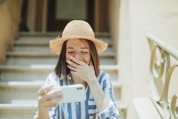 Photo of Woman Smiling While Siting on Stairs and Using White Smartphone