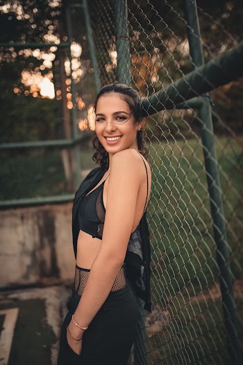 Photo of Woman Smiling While Standing Near Chain-Link Fence