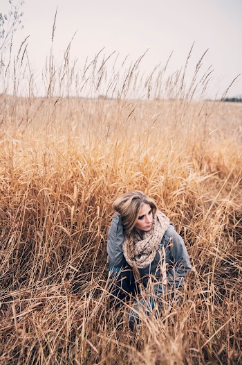 Photo of Woman Squat Posing in the Middle of Brown Grass Field Looking Away