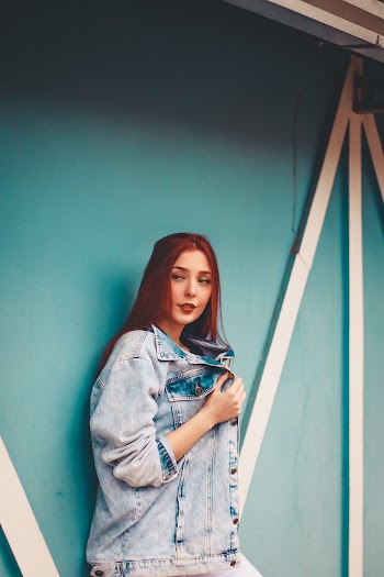 Photo of Woman Standing and Leaning on Blue Wall
