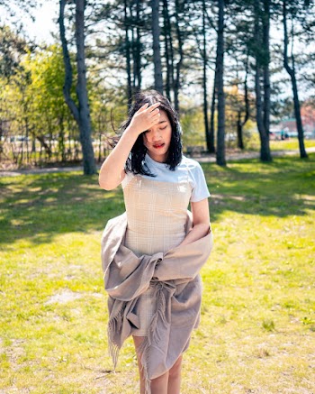 Photo of Woman Standing at the Park While Touching Her Hair Posing While Looking Down
