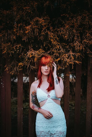 Photo of Woman Standing Behind Brown Wooden Fence