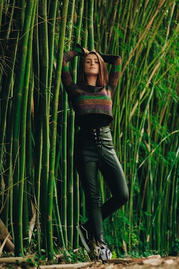 Photo of Woman Standing by Bamboo Trees Leaning on a Bamboo Tree