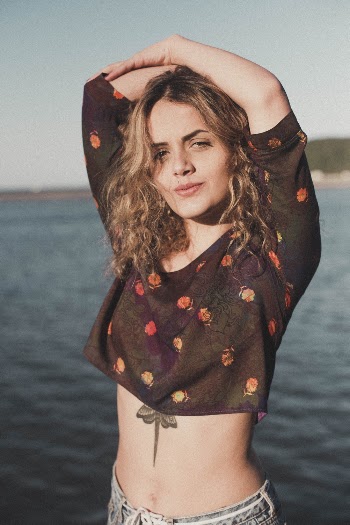Photo of Woman Standing by Body of Water Holding Her Head