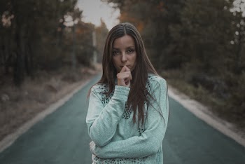 Photo of Woman Standing in The Middle of a Road Near Trees